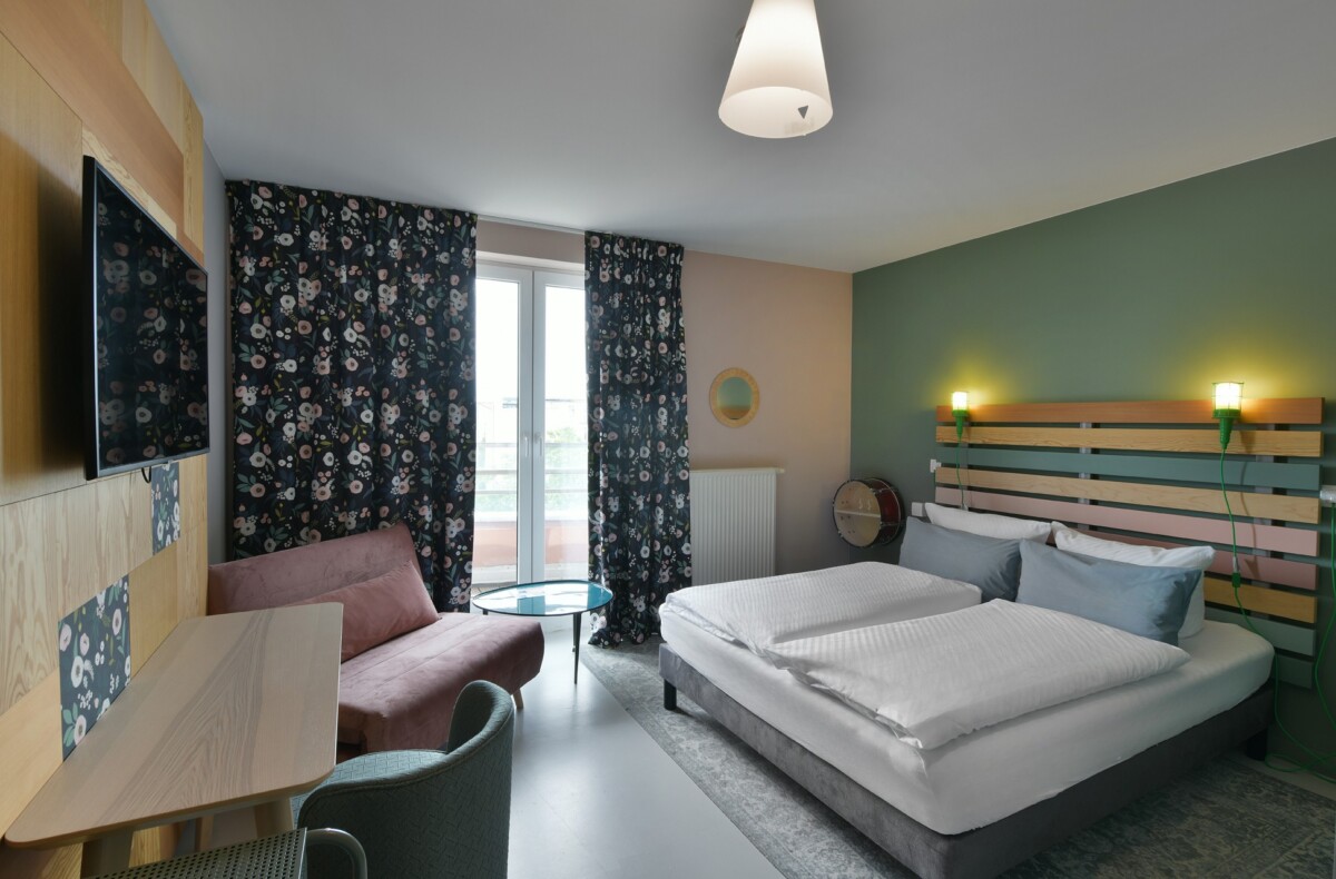 Double hotel room with TV, floral decor, and a cozy reading corner
