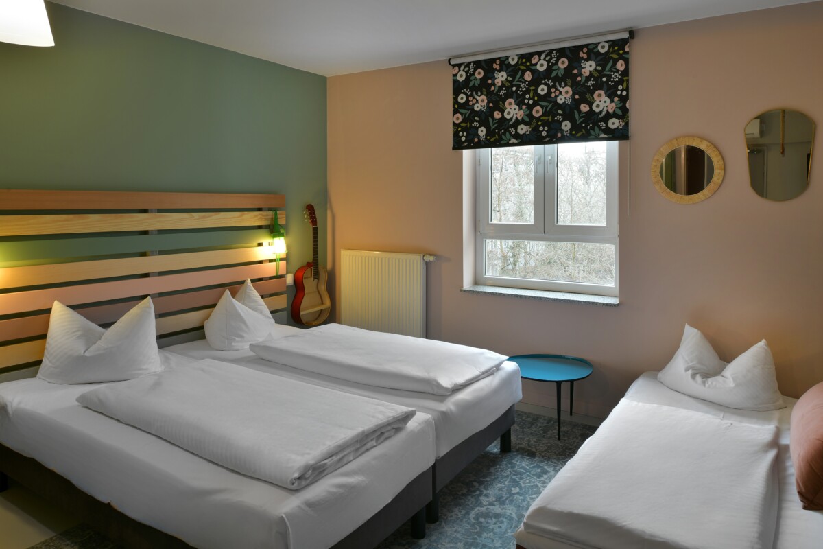 Hotel room with one double bed, one single bed, guitar, and modern decor